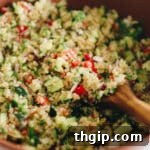 cucumbers, tomatoes, red onion, parsley and white quinoa mixed together in a brown bowl.