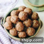 Four chocolate lavender energy balls on a white background, garnished with lavender