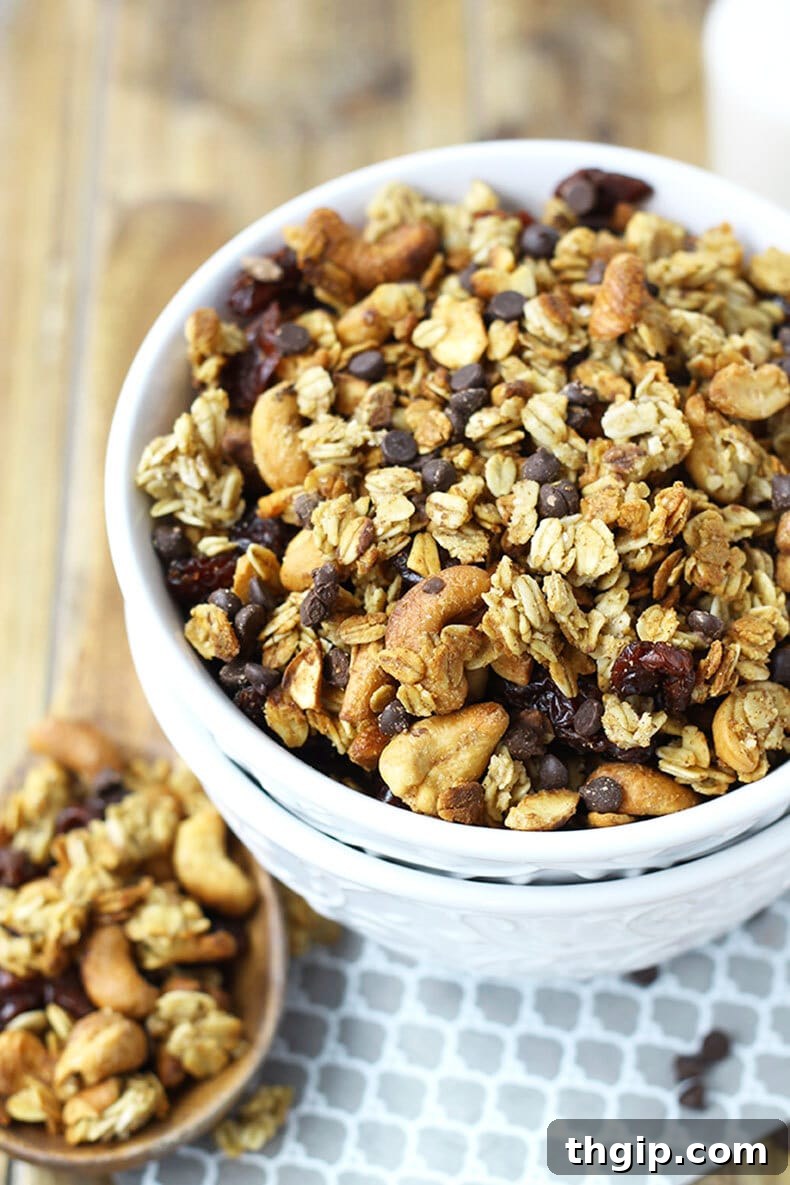 Crimson Cherry Chocolate Granola 4 Homemade chocolate cherry granola cooling on a baking sheet, with dried cherries and chocolate chips on top.