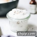 A mason jar with a homemade salt scrub, surrounded by ingredients.