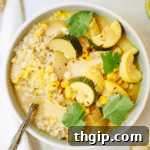 A bowl of vibrant green summer veggie curry with white rice.