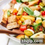 A rustic bowl of Summer Panzanella Salad, featuring grilled zucchini, peaches, tomatoes, and toasted bread.