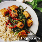 A bowl of Thai Basil Tofu Stir-fry with rice, basil, and sesame seeds.