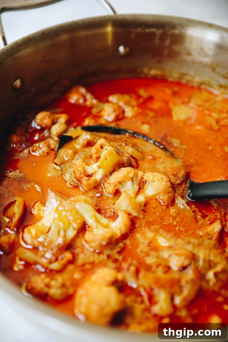 The Massaman curry simmers in a pot with coconut milk, chickpeas, and spices, developing a rich, thick sauce.