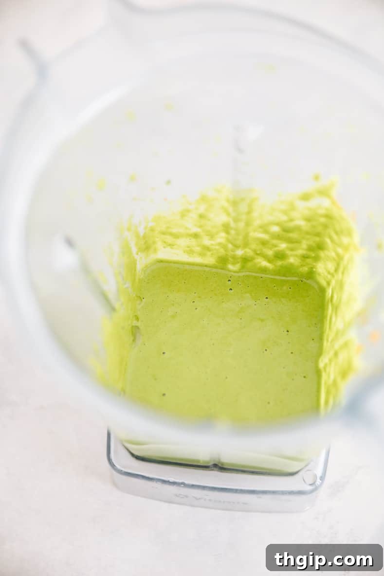 Whip Up Your Own Zhug Skhug Yemeni Hot Sauce 4 Smooth, vibrant green Zhug sauce in a glass jar with a spoon, ready to be stored.