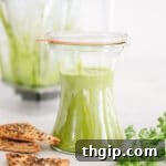 A top-down view of freshly made green Zhug sauce in a bowl, with a spoon taking a scoop.