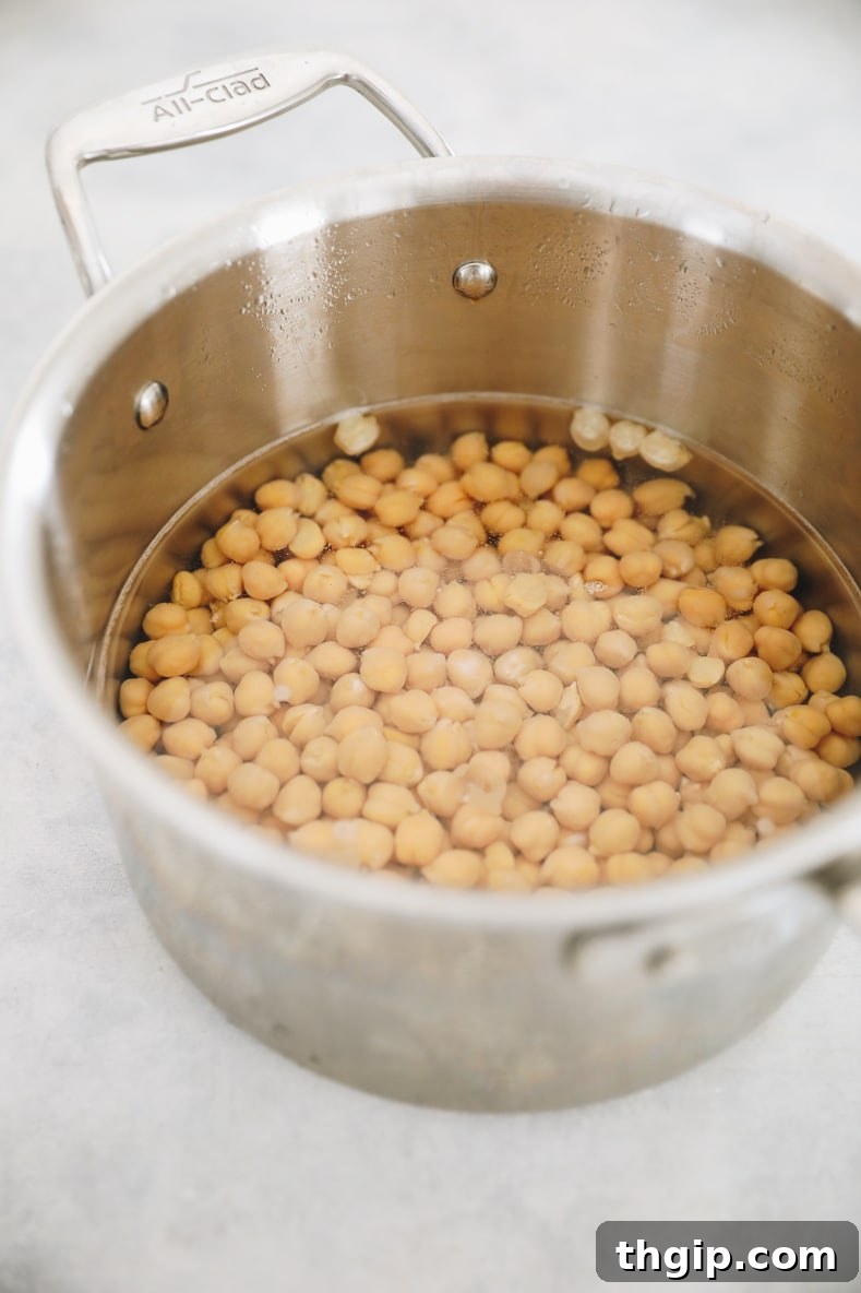 Dreamy Creamy Hummus 4 Soaked and cooked chickpeas simmering gently in a pot on the stovetop, a crucial step for achieving tender legumes.