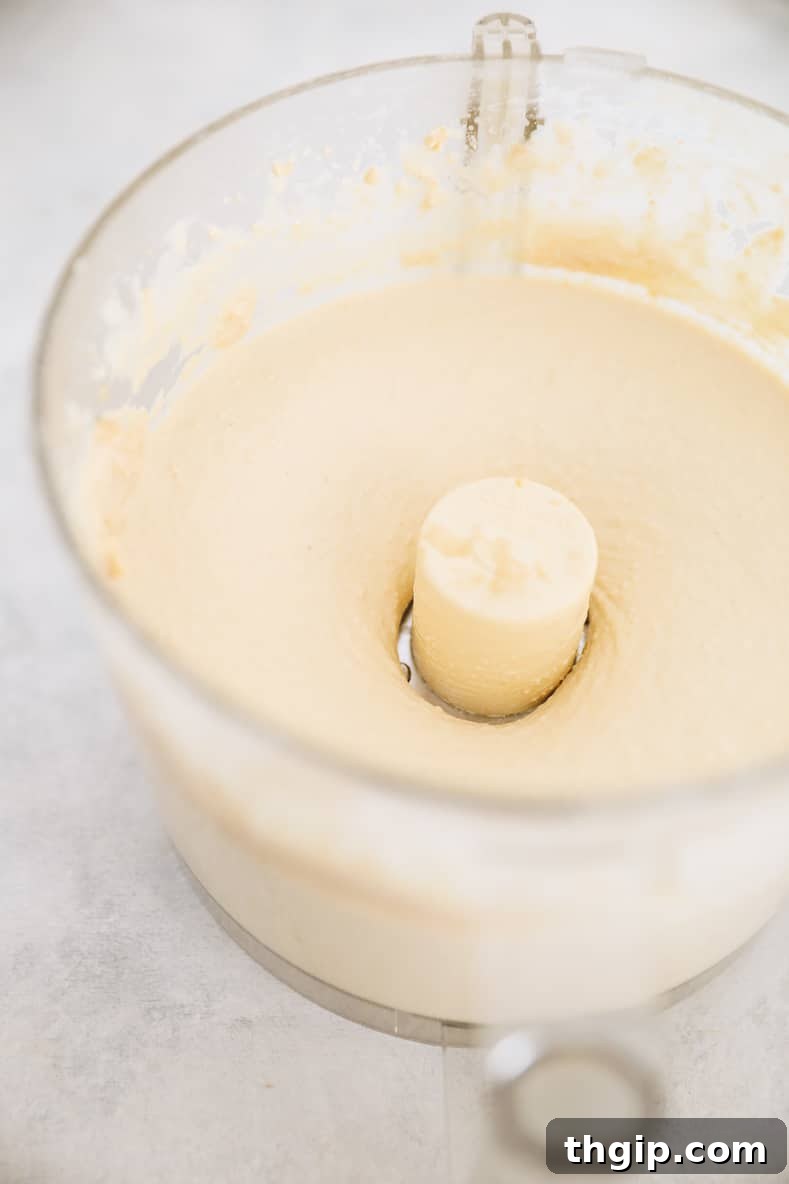 Dreamy Creamy Hummus 6 Beautifully blended creamy homemade hummus swirling inside a food processor, showcasing its smooth and airy texture.