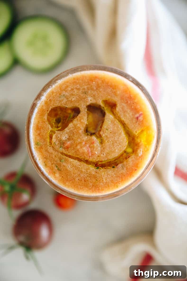Simple Summer Gazpacho 2 A glass of vibrant red gazpacho soup with fresh vegetable garnishes.