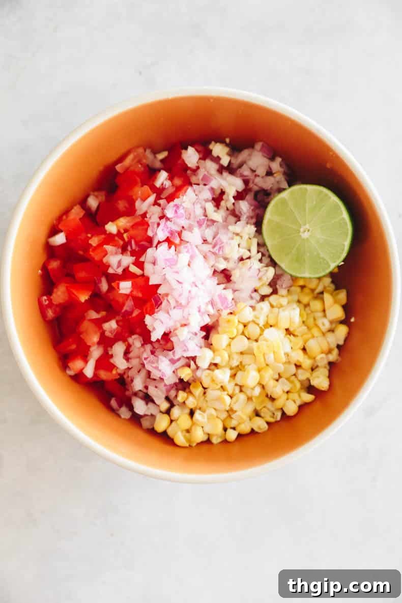 Summer Corn Salsa 4 Fresh corn salsa mixed in a large glass bowl, showcasing the colorful ingredients.