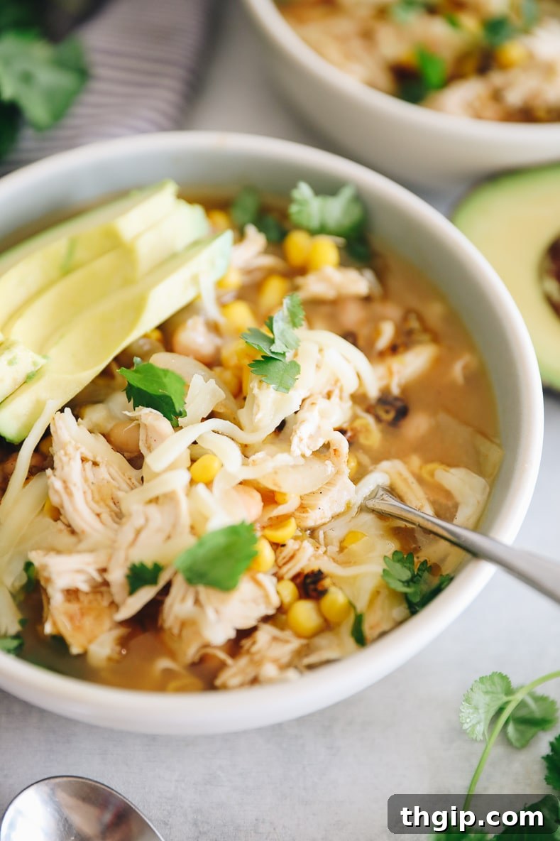 Creamy Instant Pot White Chicken Chili 7 A wide shot of a pot of Instant Pot White Chicken Chili being stirred, with various toppings on the side.