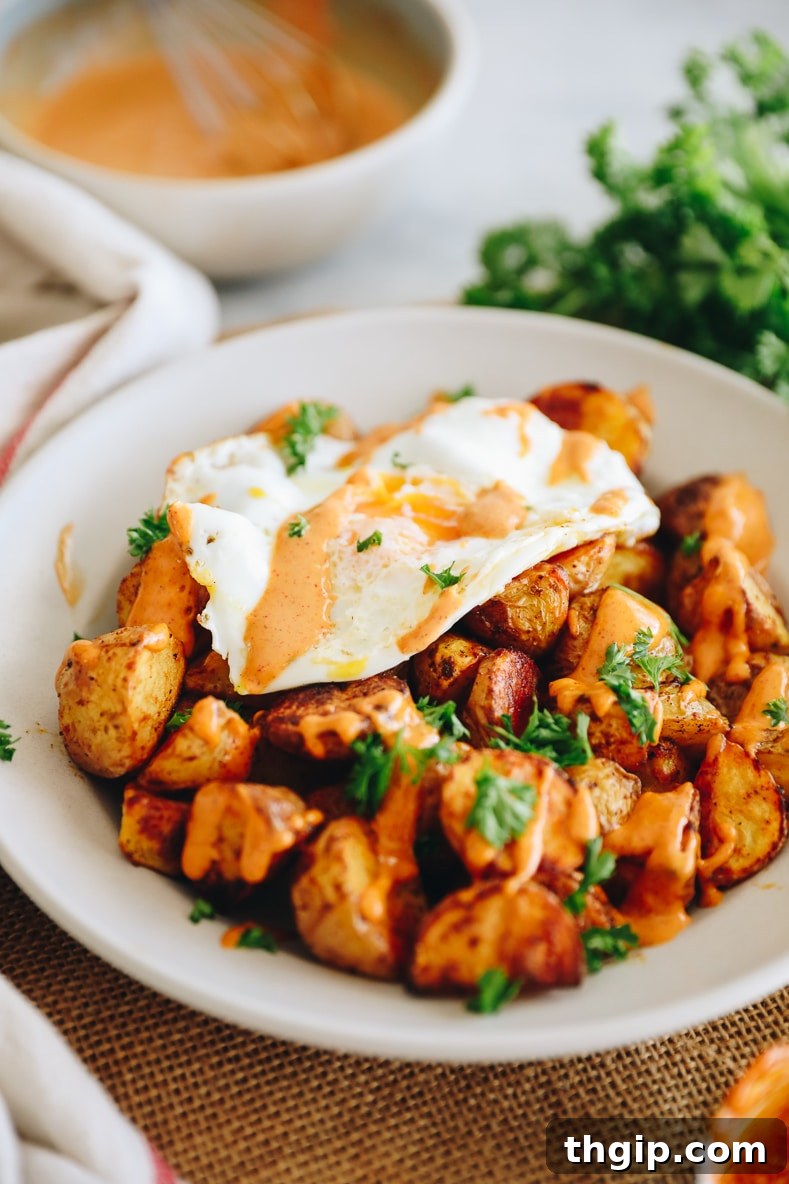 Breakfast Bravas Skillet 2 Crispy baked potatoes with chipotle garlic aioli and a fried egg, garnished with parsley.