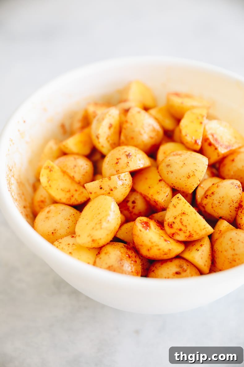 Breakfast Bravas Skillet 3 Chopped baby potatoes tossed with olive oil and spices in a bowl, ready for baking.