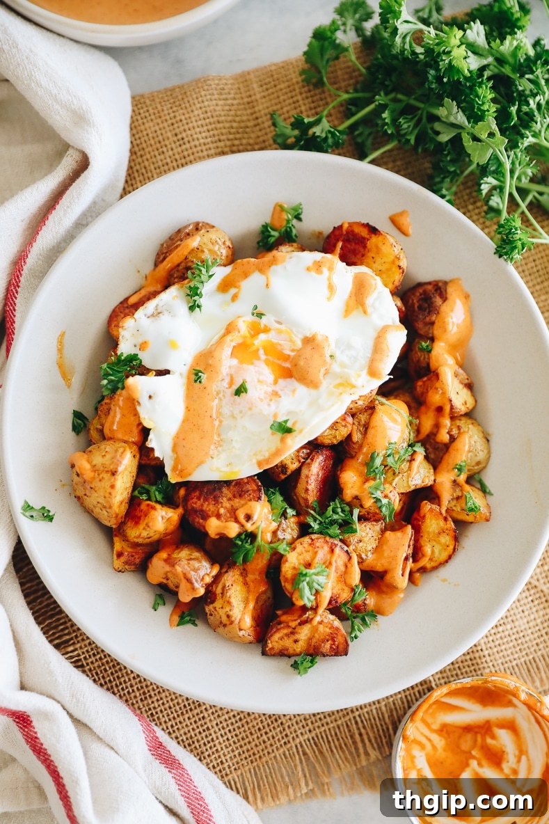 Breakfast Bravas Skillet 7 A close-up of the breakfast patatas bravas with a perfectly cooked fried egg and drizzled aioli, ready to eat.