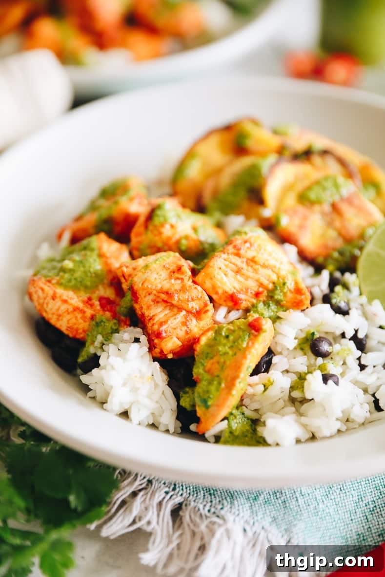 Assembled Piri Piri Chicken Bowl with rice, black beans, chicken, plantains, and green sauce.