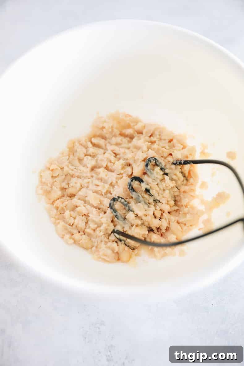 Wholesome Quinoa Veggie Burgers 4 Mashing cannellini beans in a bowl for the quinoa burger mixture.