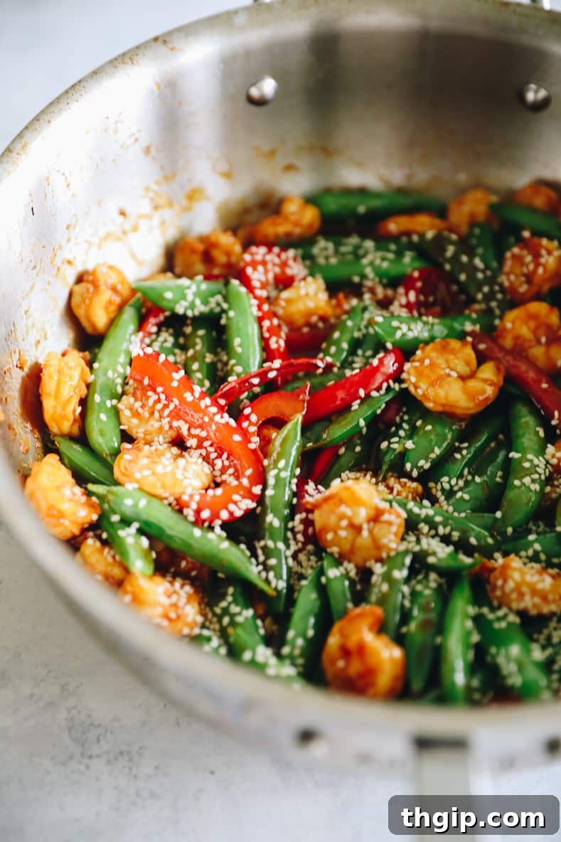 Sizzling Sesame Shrimp with Crisp Vegetable Stir-Fry 8 Finished spicy sesame shrimp and veggie stir fry served over rice in a bowl