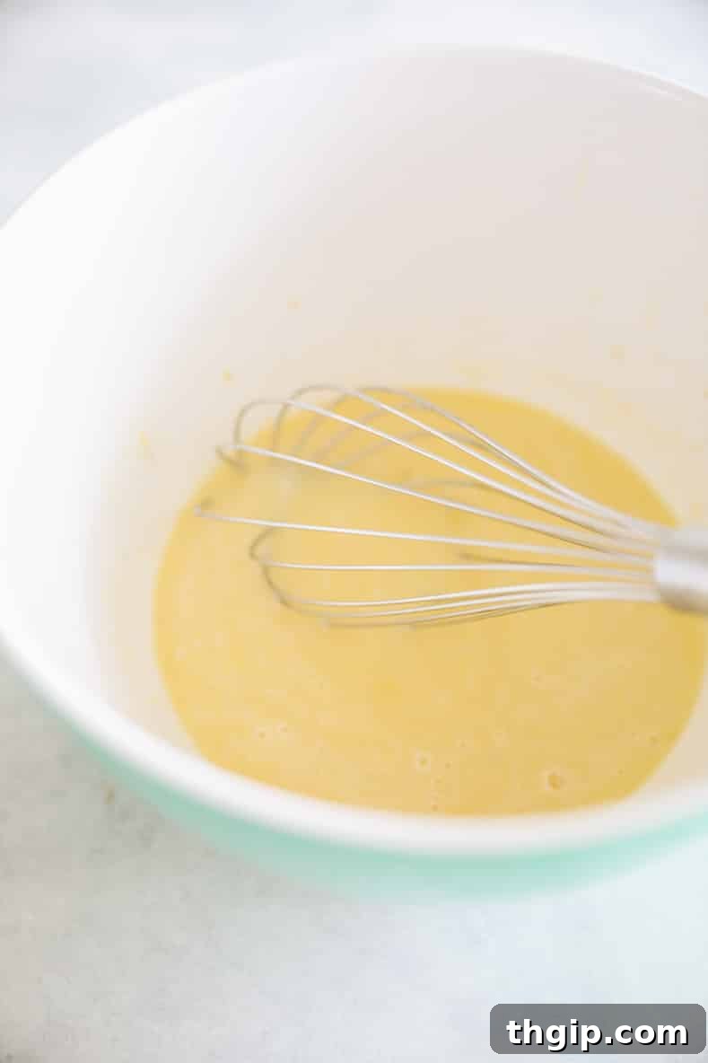 Garden Gem Chocolate Muffins 5 A bowl of wet ingredients for chocolate zucchini muffins: melted butter, honey or maple syrup, applesauce, egg, almond milk, and vanilla extract, thoroughly whisked together.