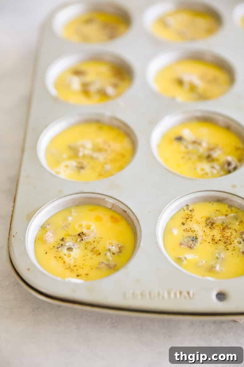 Muffin pan filled with vegetable and egg mixture.