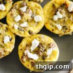 Close up shot of egg muffins topped with goat cheese, indicating a prepared dish.