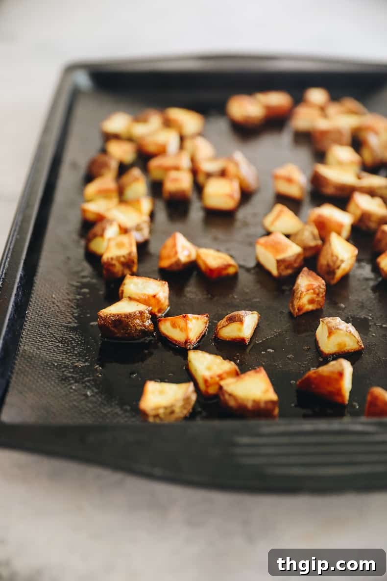 Grab-and-Go Frozen Breakfast Burritos 3 Cubed russet potatoes tossed with olive oil and salt on a baking sheet, ready for roasting for breakfast burritos.