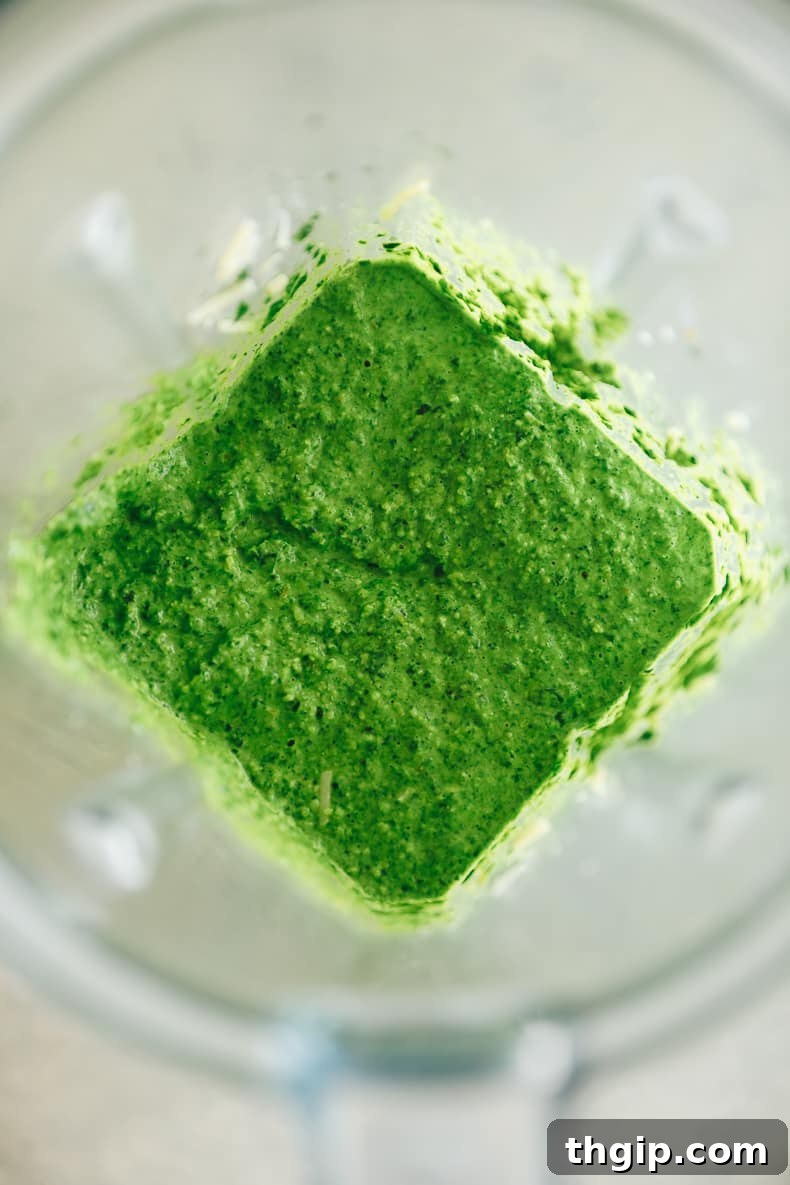 Verdant Kale Pesto Pasta 3 Freshly blanched kale and other ingredients being blended into a smooth pesto in a food processor.