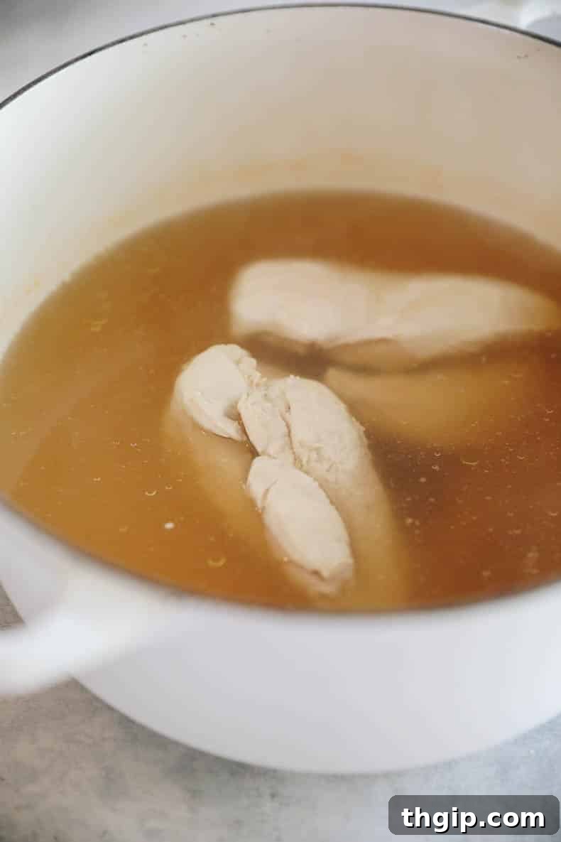 Chicken breasts poaching in a large pot of chicken broth for pozole.