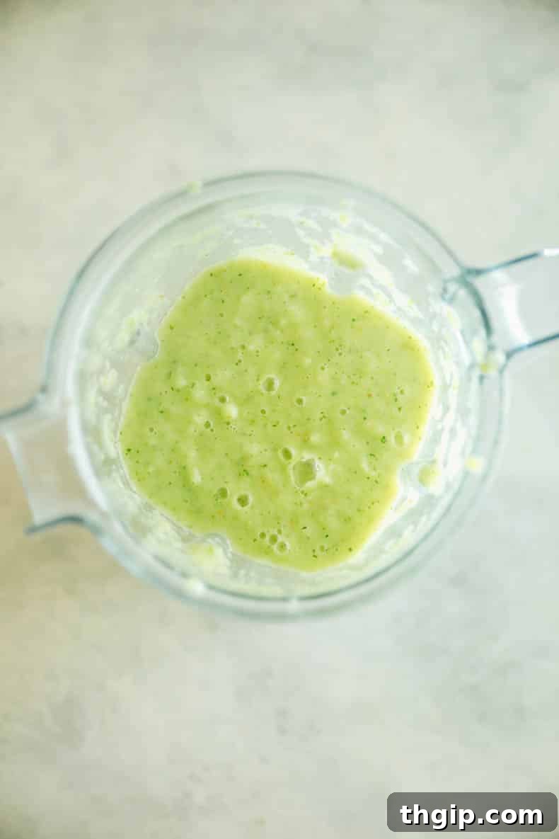 Vibrant green sauce for pozole verde being blended in a high-speed blender.