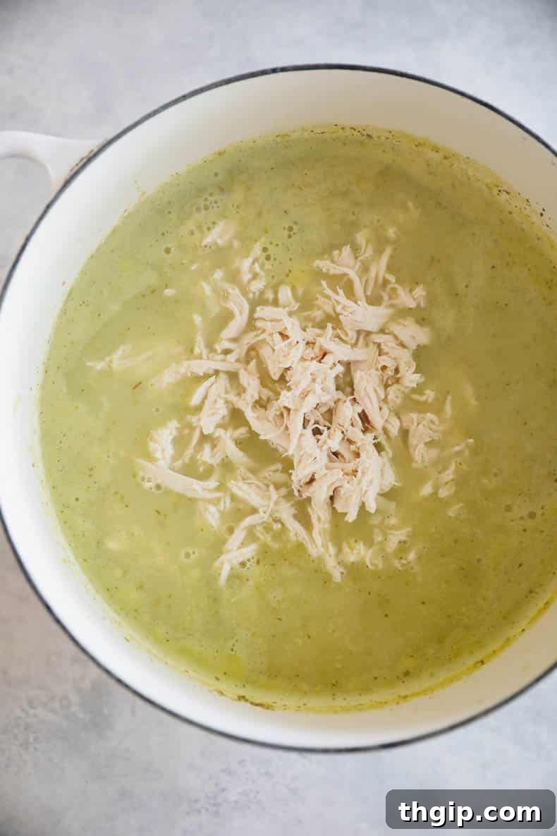 Large Dutch oven filled with simmering green chicken pozole, rich and fragrant.