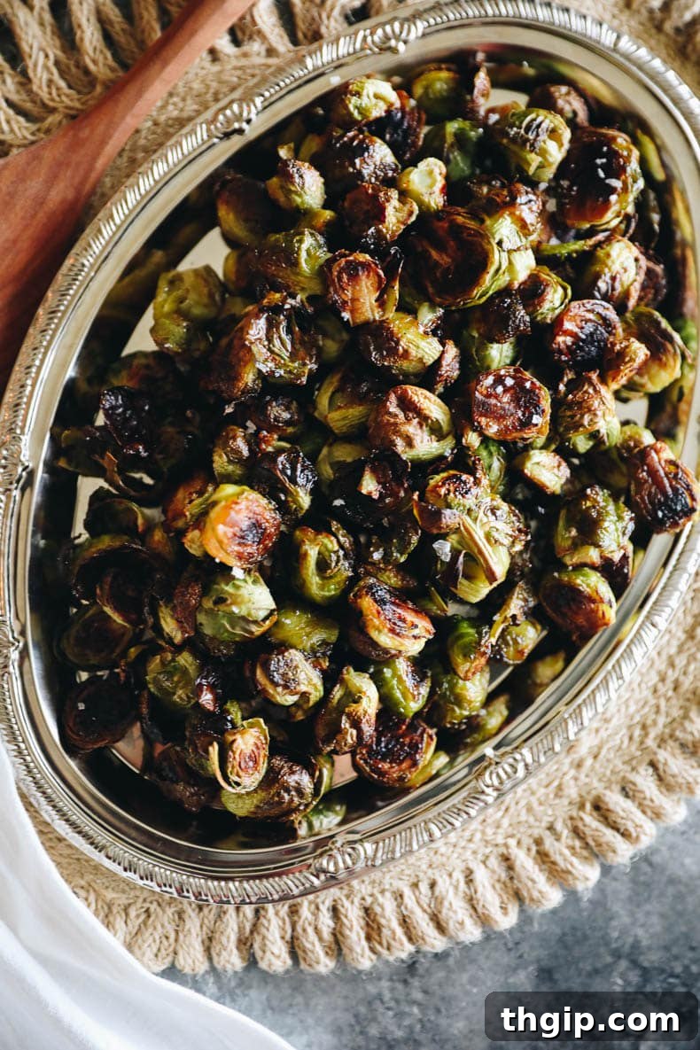 Perfectly roasted Brussels sprouts presented in an elegant silver serving dish, ready to be enjoyed.