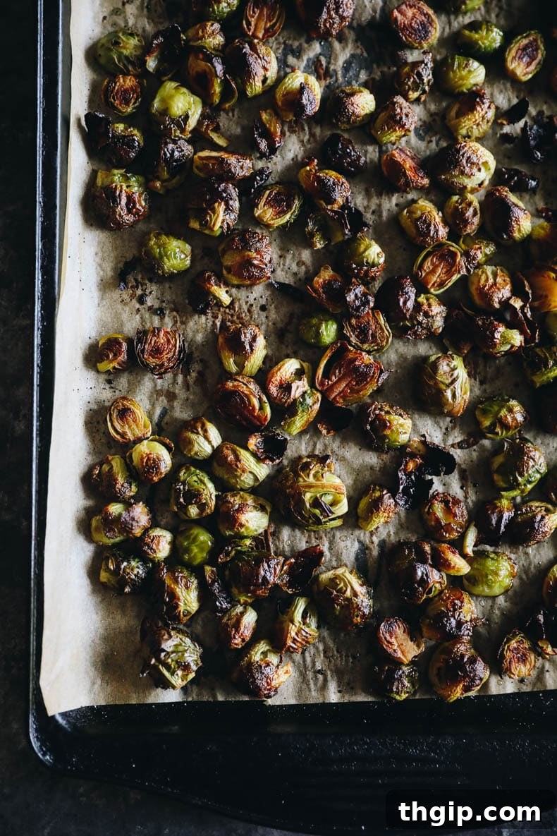 Overhead photograph of beautifully roasted Brussels sprouts with balsamic glaze on a sheet pan, showcasing their crispy texture.