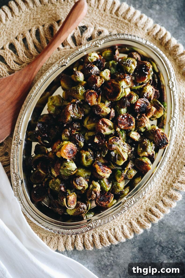 Beautifully roasted balsamic glazed Brussels sprouts piled high on a rustic silver platter, garnished for serving.