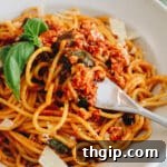 Up-close photo of tofu pasta on a fork in a white bowl, ready to eat.