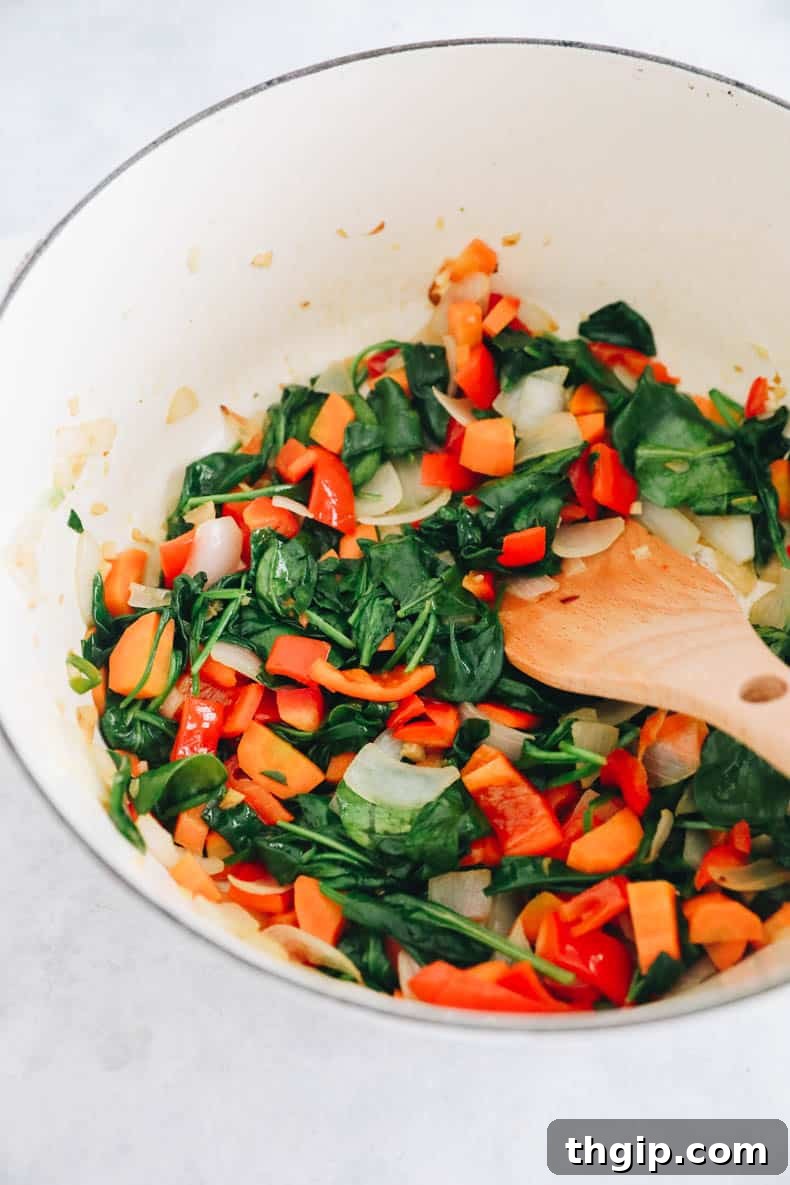 Secret Garden Pasta Sauce 4 Cooked onion, garlic, carrot, red bell pepper, and wilted spinach simmering together in a white Dutch oven.