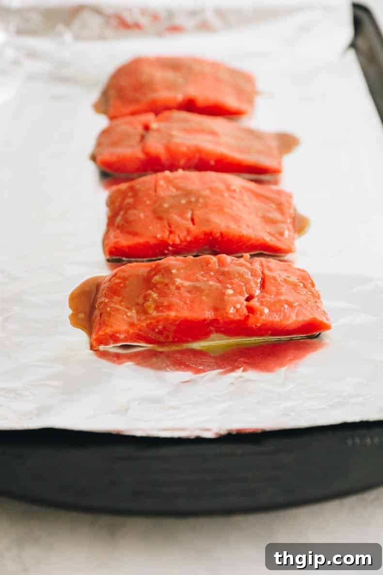 Effortless Miso Glazed Salmon 5 fresh salmon marinated with miso glaze on a baking sheet lined with tinfoil.