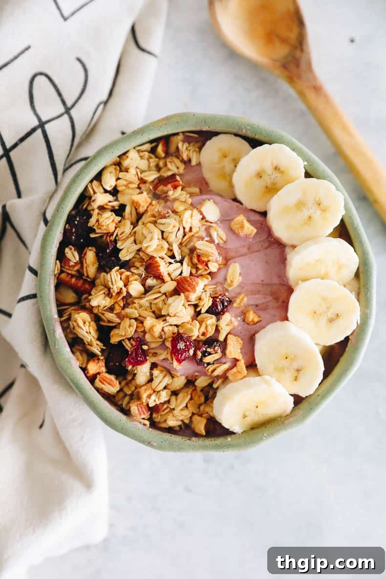 Vibrant Bowl Blends 2 A vibrant pink berry smoothie bowl garnished with fresh banana slices and crunchy granola, ready to be enjoyed as a healthy breakfast.