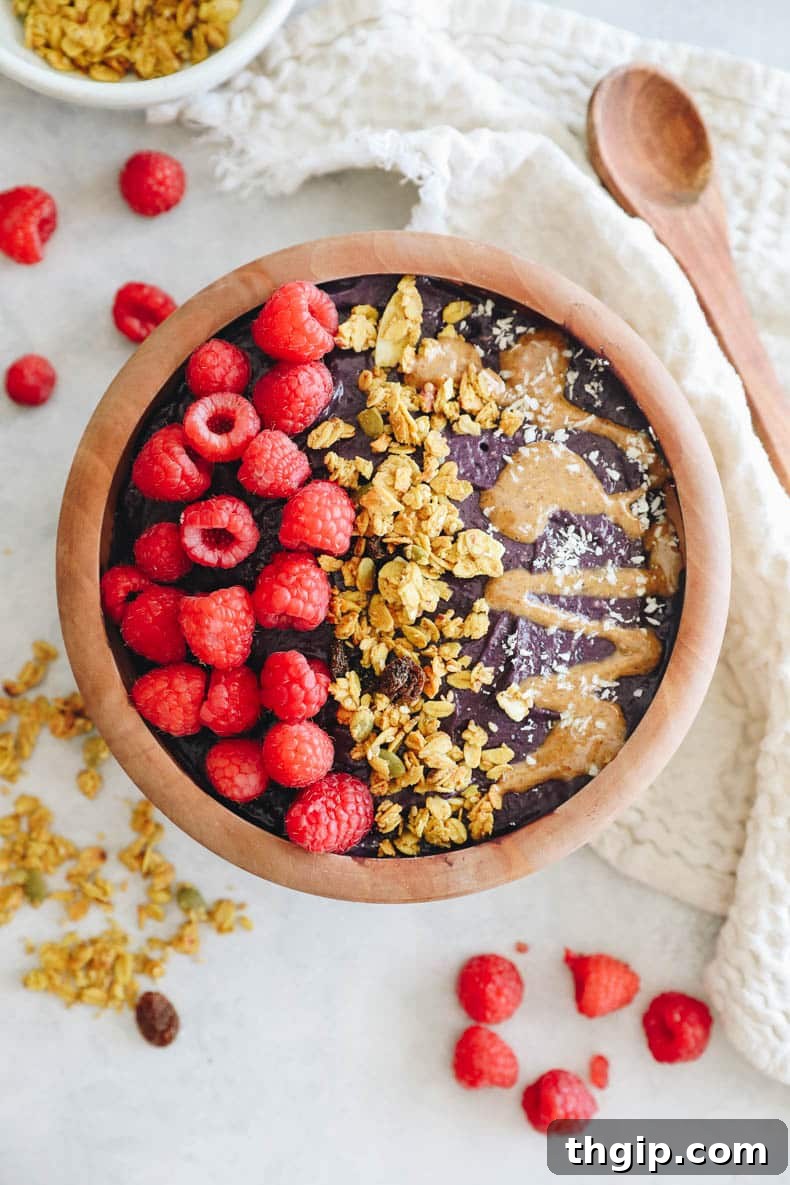 Superfood Acai Bliss Bowl 2 acai bowl recipe in a wooden bowl topped with raspberries, granola and almond butter.