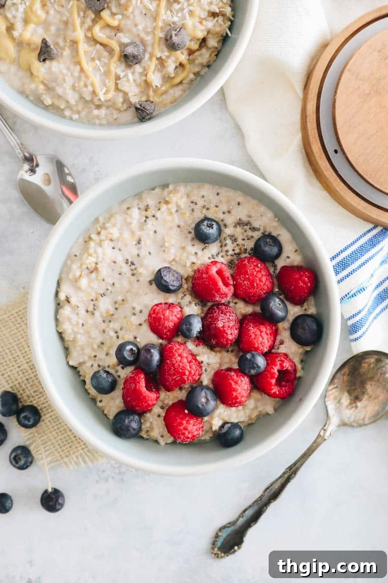 overhead photograph of overnight steel cut oats in two bowls. One bowl is topped with raspberries, blueberries and chia seeds. The other bowl is topped with chocolate chips, peanut butter and coconut.