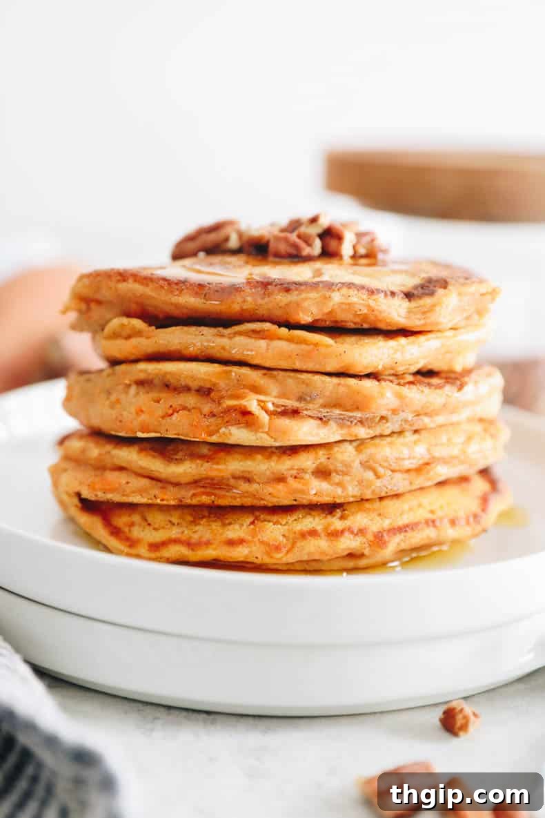 Golden Yam Griddlecakes 8 stack of sweet potato pancakes on a white plate topped with pecans.
