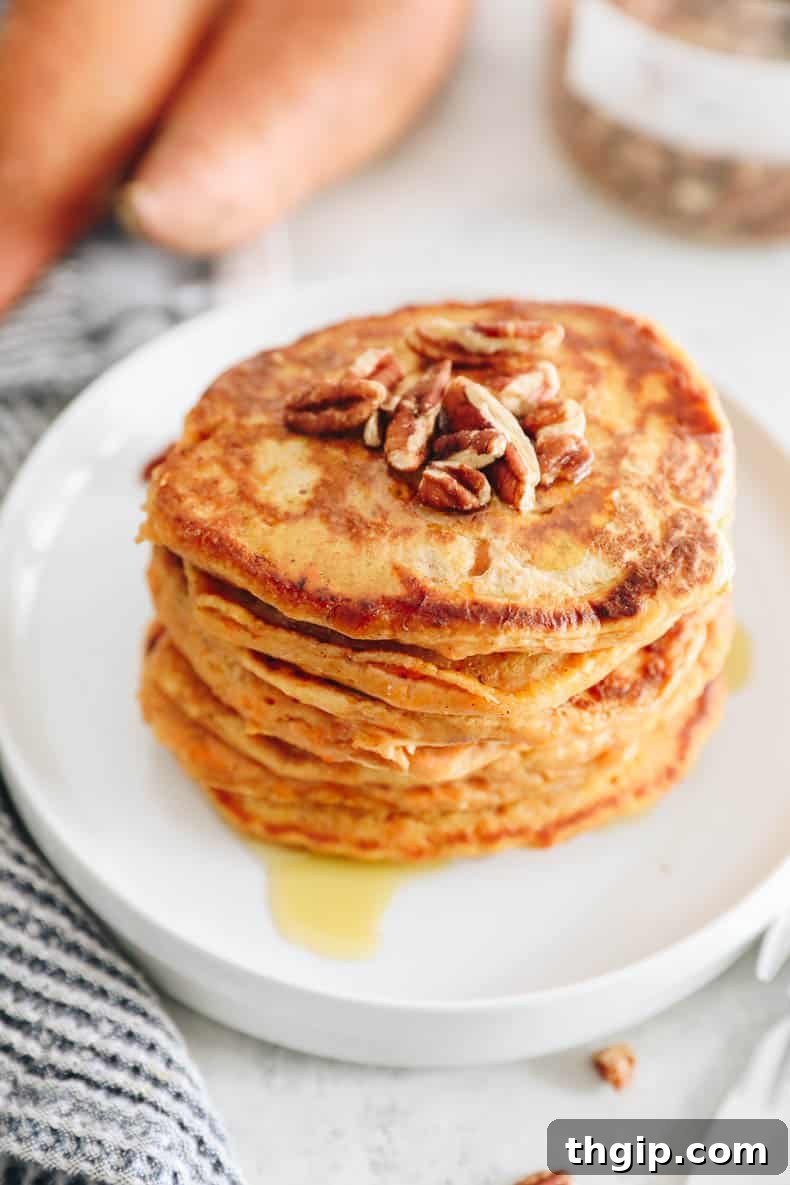 Golden Yam Griddlecakes 10 stack of sweet potato pancakes that are orange on a white plate.
