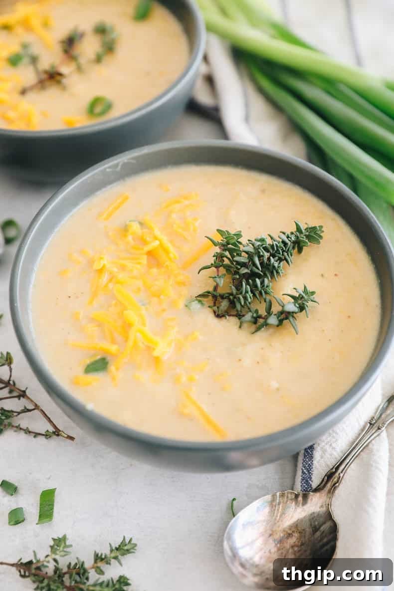 Golden Roasted Cauliflower Soup 2 roasted cauliflower soup in a blue bowl topped with fresh thyme and cheddar cheese.