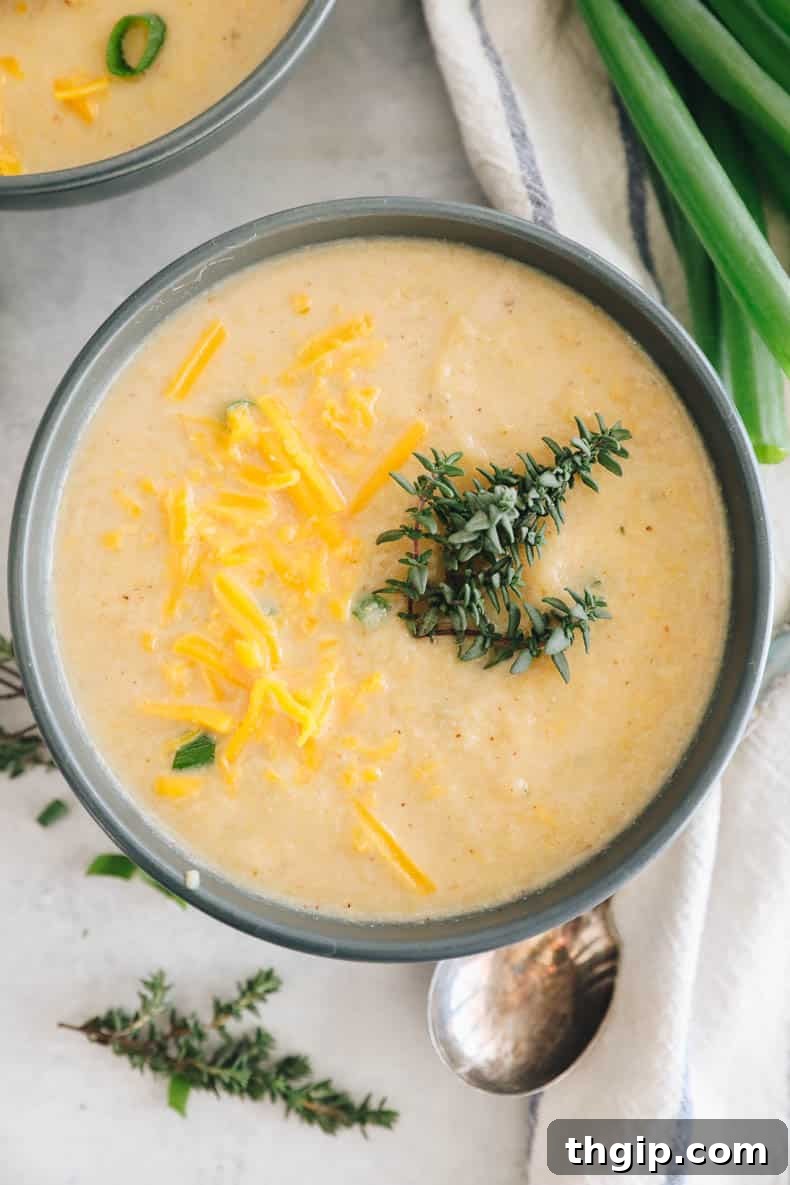 Golden Roasted Cauliflower Soup 7 roasted cauliflower soup in a blue bowl topped with fresh thyme and cheddar cheese.