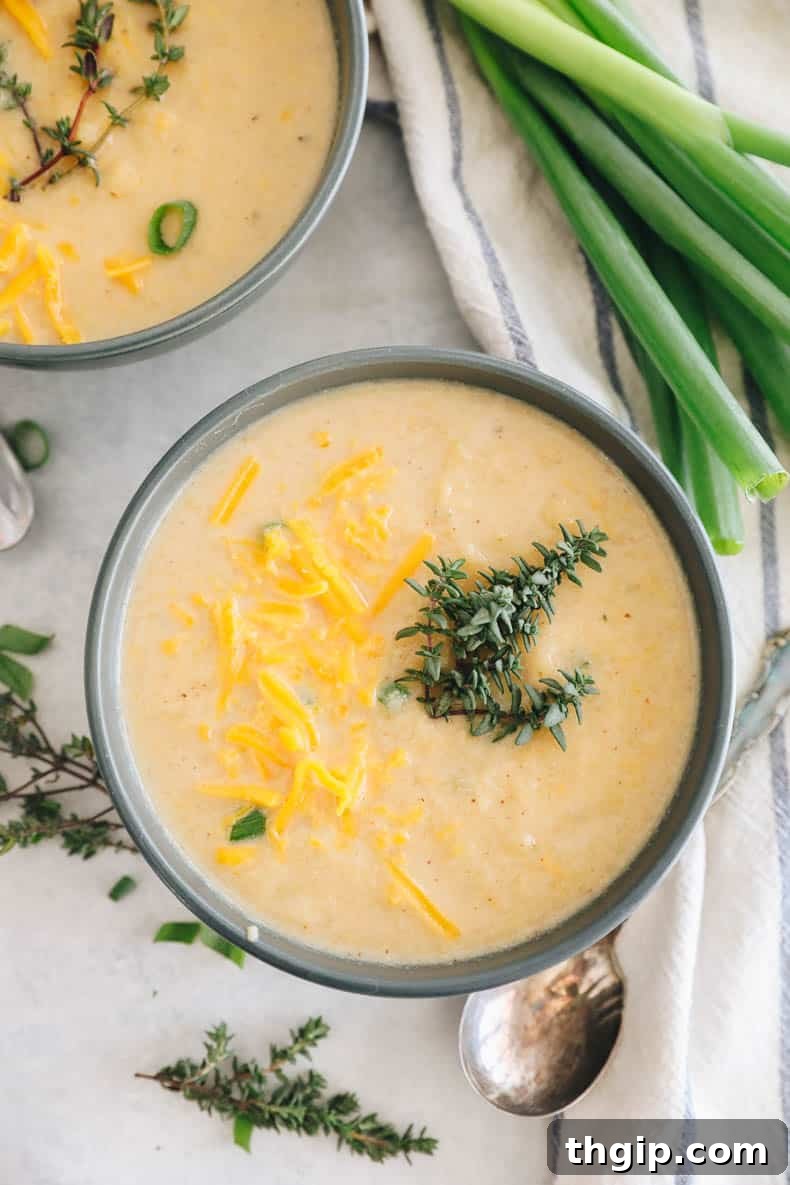 Golden Roasted Cauliflower Soup 9 roasted cauliflower soup in a blue bowl topped with fresh thyme and cheddar cheese.