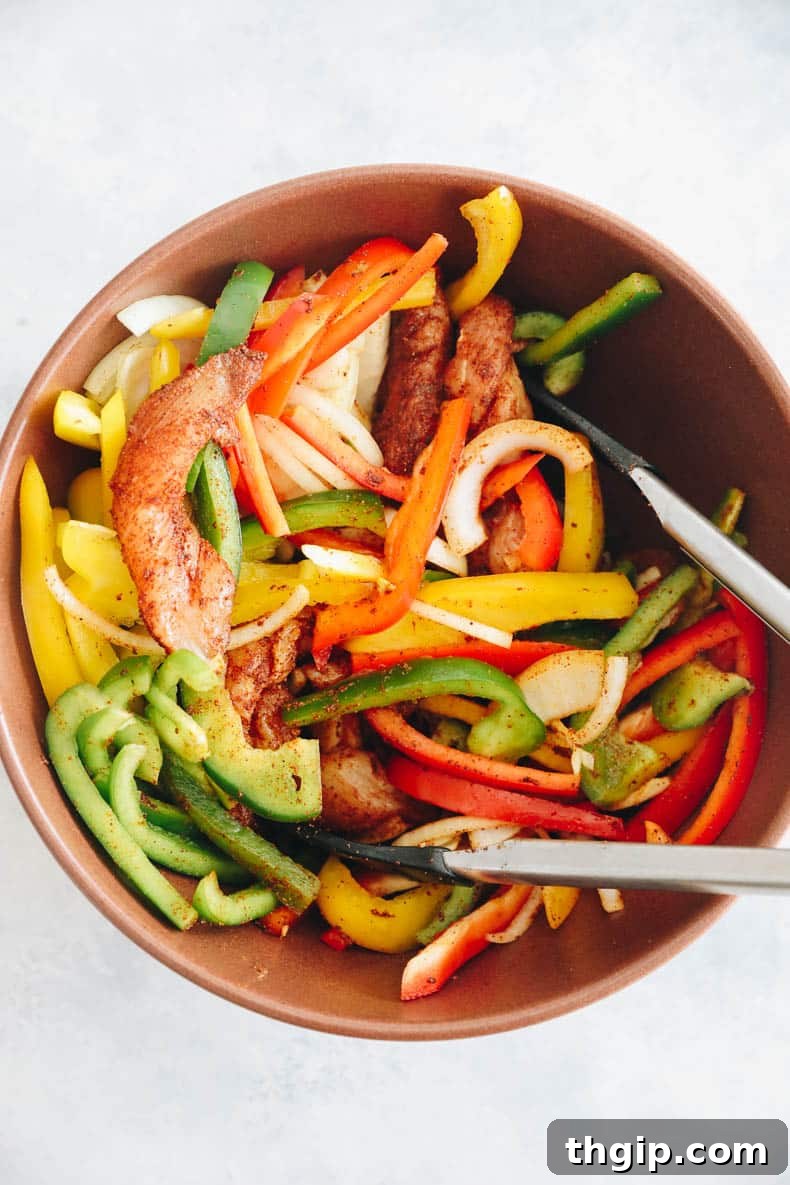 Effortless Fajita Feast 4 Chicken and vegetables tossed in fajita seasoning and olive oil in a large bowl.