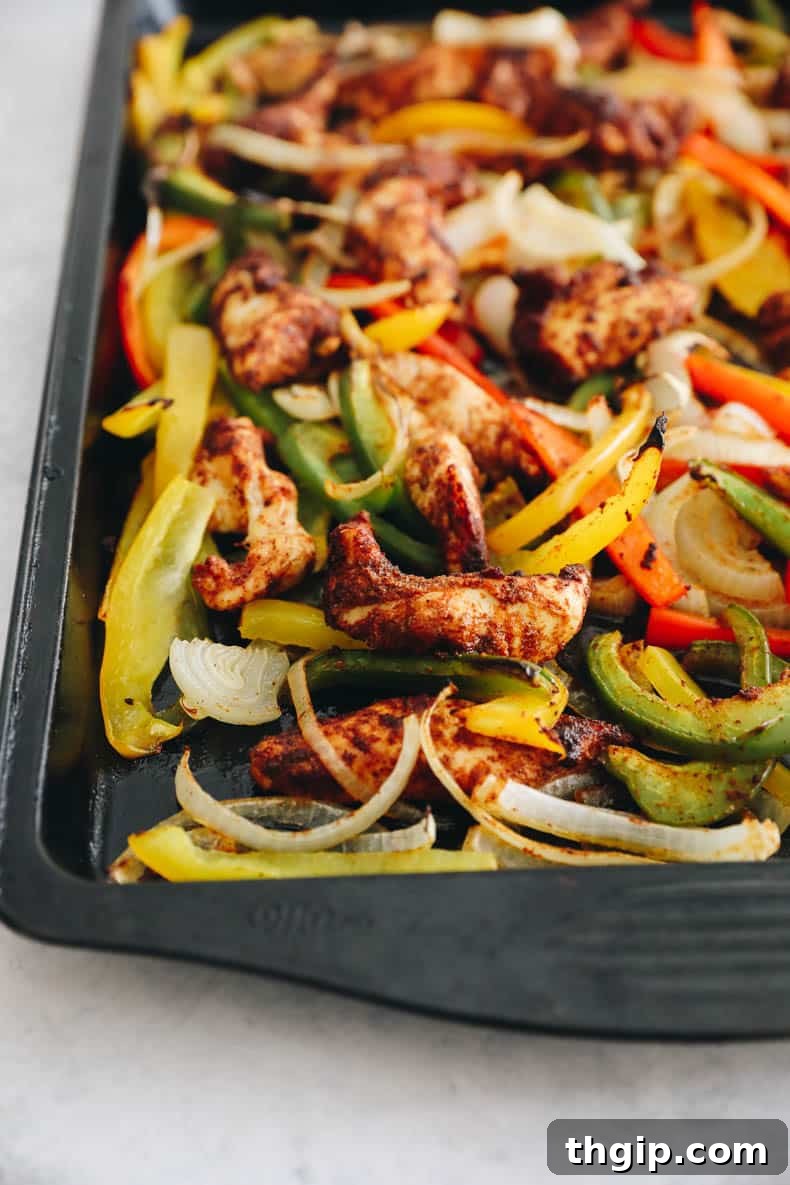 Effortless Fajita Feast 5 Roasted chicken and vegetables in fajita seasoning spread on a sheet pan, fresh out of the oven.