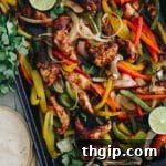 Sheet pan fajitas on a roasting pan with bell peppers and onions, ready for serving.