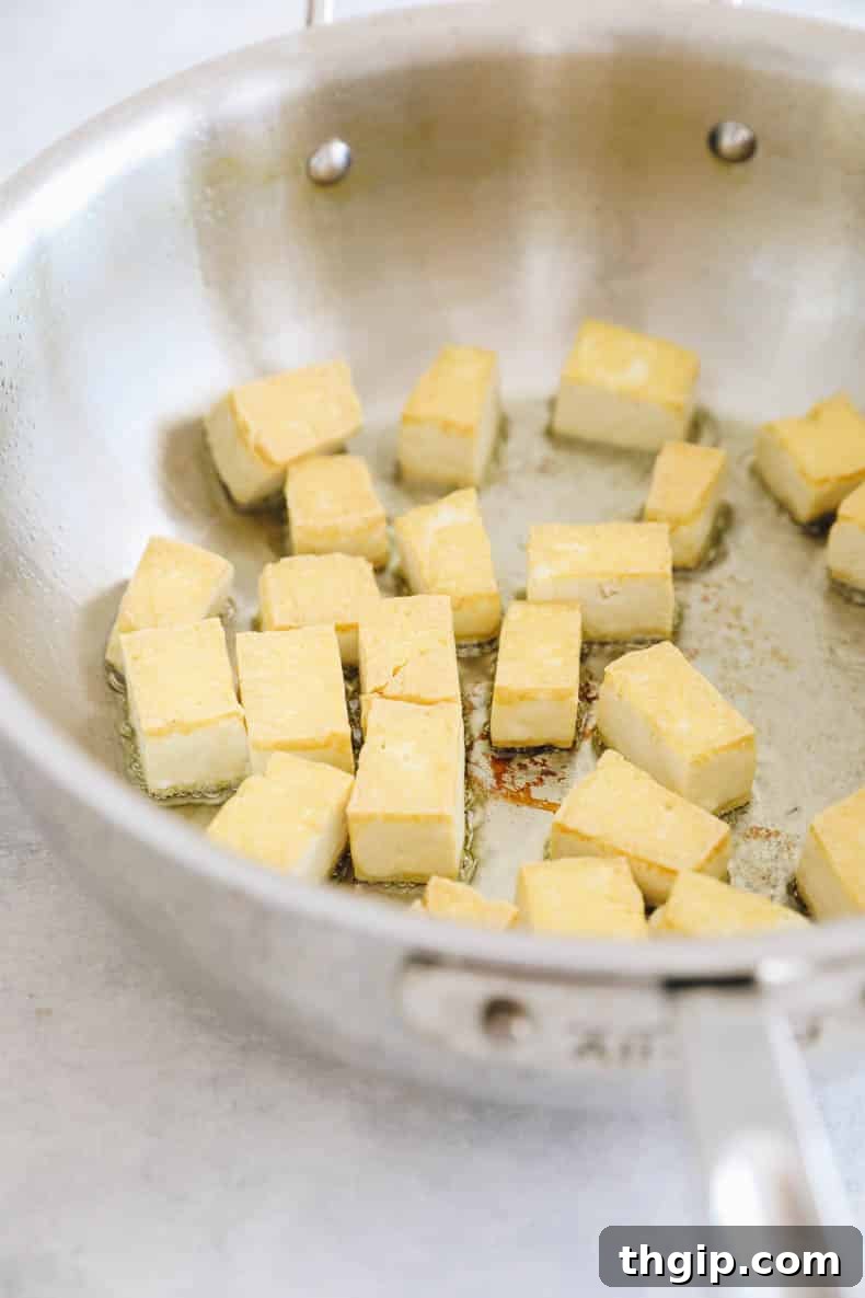 Golden Coconut Tofu Curry 3 Tofu cooking in a skillet, turning golden brown and crispy.