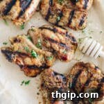 Grilled honey mustard chicken on a plate sprinkled with parsley.