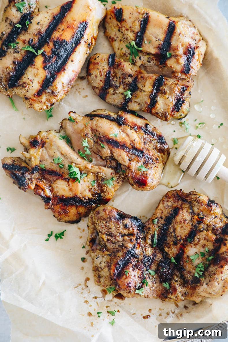 Finished honey mustard chicken on a white plate, garnished with fresh herbs.
