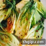 pan fried garlic baby bok choy on a plate with red pepper flakes.
